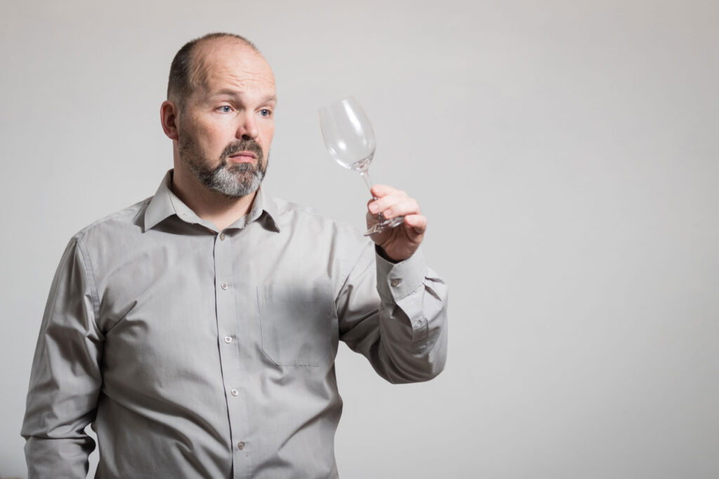 Man looks at smudged wine class and wonders how to help someone with a drinking problem