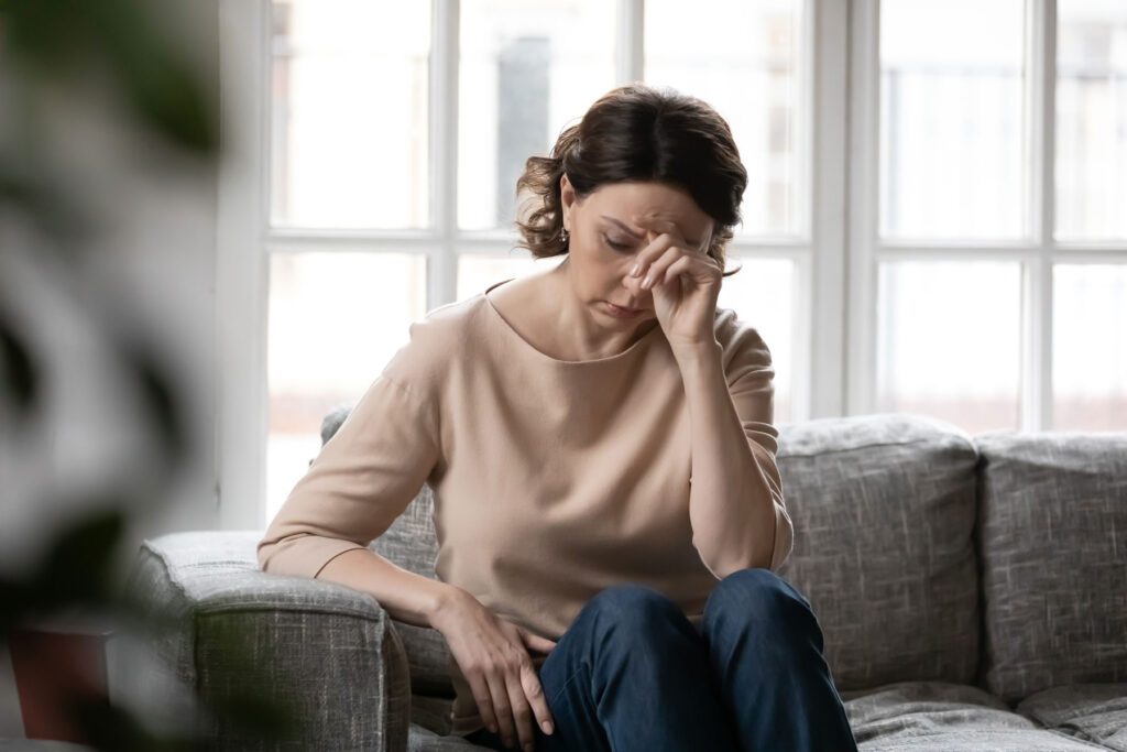 Woman sits on couch as she thinks about signs of addiction in women